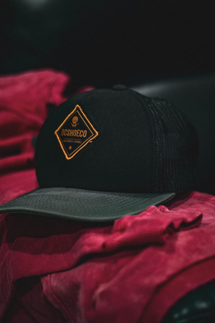 Close-up of a black cap with logo resting on vibrant red fabric.