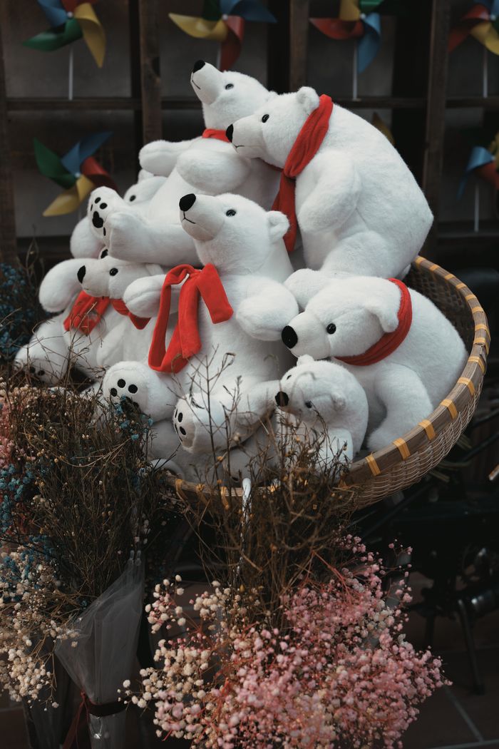 Services Charming display of plush polar bears in a cozy basket surrounded by dried flowers.
