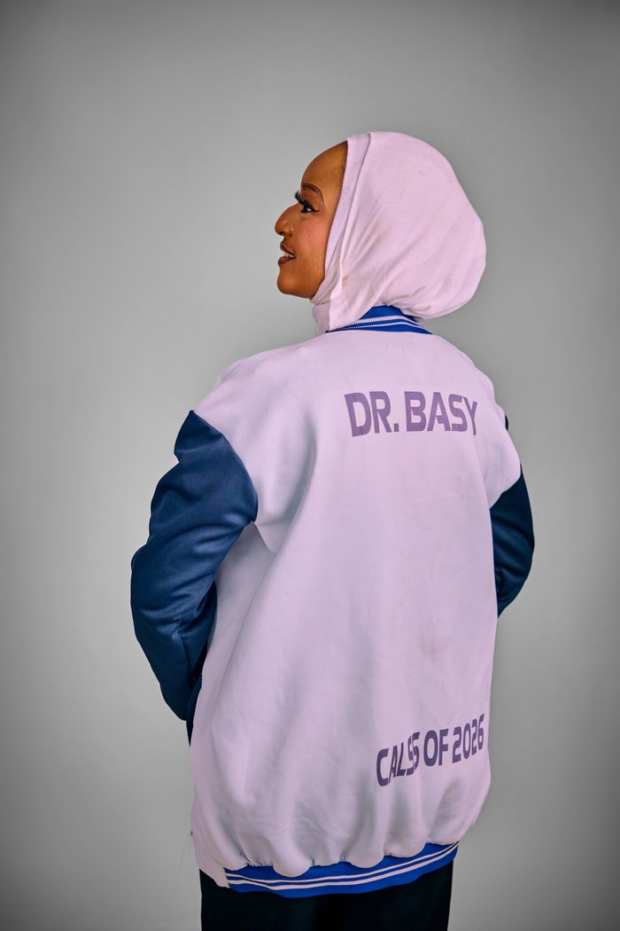 Home Woman in a custom jacket with 'Dr. Basy' and 'Class of 2026' text, looking confident.