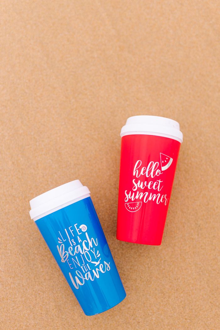 Services Blue and red reusable tumblers with summer quotes on sandy background.